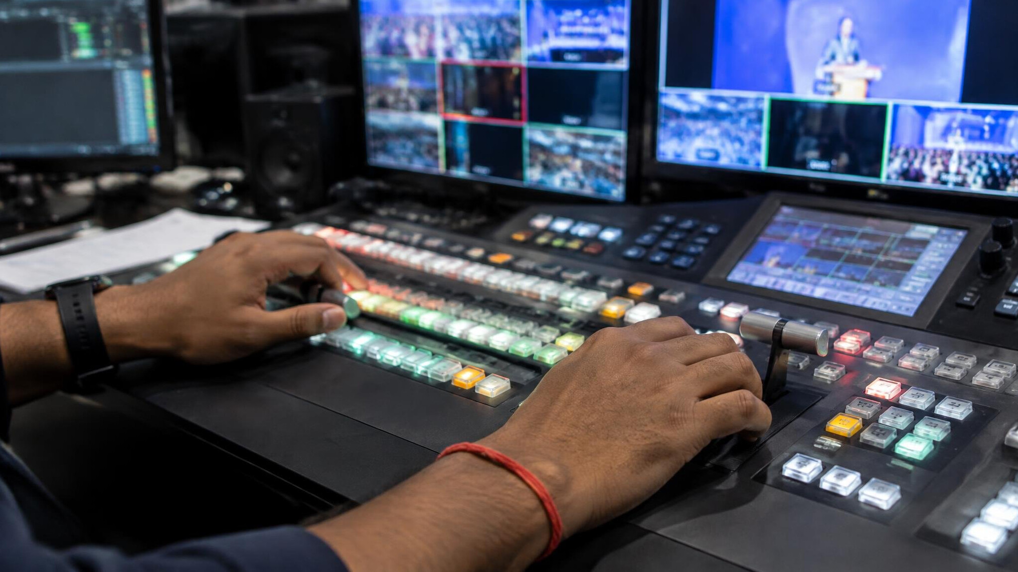 Close-up of hands operating a video switcher console